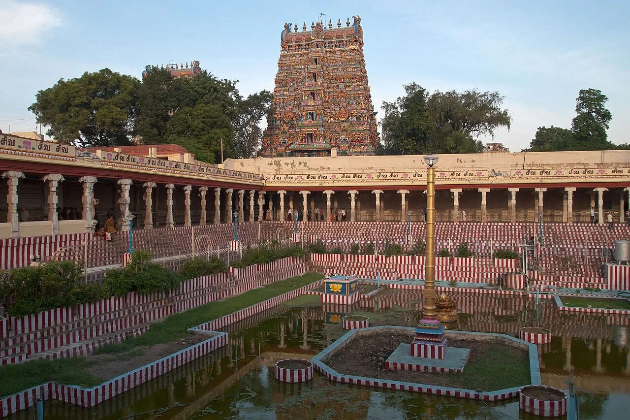 A carved gopuram and the courtyard pool at Meenakshi Amman Temple in Madurai